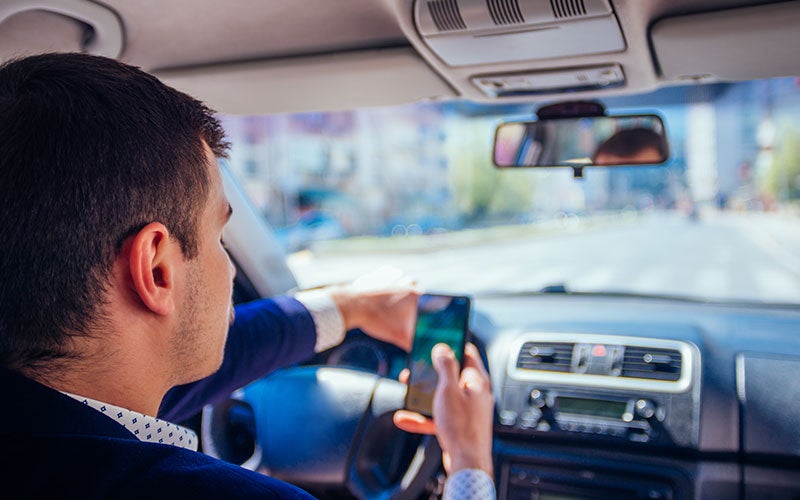 Man driving recklessly while using mobile phone on road